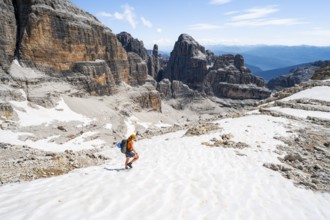 Female mountaineer in a snowfield on the Sella della Tosa, mountain landscape with steep cliffs,
