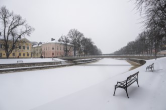 Benches, historic buildings on the frozen Aurajoki River, wintery Turku or Swedish Åbo,