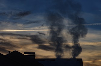 Smoking chimney of a residential building in winter, sunset, environmental pollution, Mondseeland,