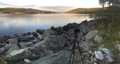 Drevsjø, Innlandet, Norway, scene of a photographer on a rocky lakeside at sunset, Gutulia National