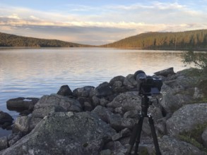 Drevsjø, Innlandet, Norway, camera on a tripod on a lake shore of Gutulsjön made of stones with