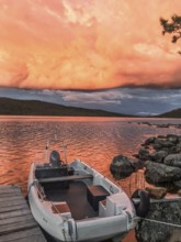 Boat moored on a jetty under a dramatic, colorful sky, Gutulia National Park, Engerdal, Innlandet,