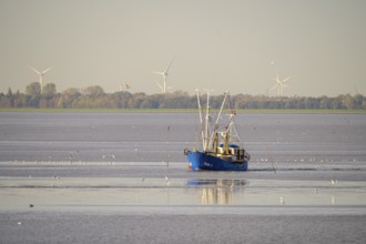 A fishing boat fishing trawler fishing trawler in the sea with wind turbines in the background and