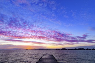 A footbridge leads into Lake Dümmer, above it a colorful sky at sunset, Dümmer nature park Park,