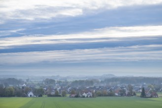 Extensive landscape with a village, fields, houses and cloudy sky in the morning,