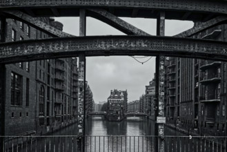 A black and white view of a bridge over a canal surrounded by historic buildings