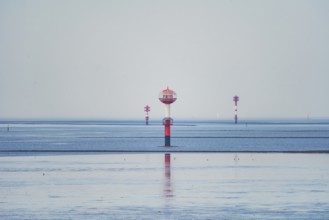 A red and white water buoy in the vast blue sea under a bright sky