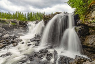 Mighty waterfall falling over rocky cliffs in a wooded area