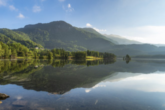 Idyllic mountain lake with a clear reflection of the surrounding wooded mountains