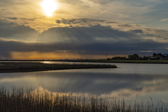 Atmospheric landscape with a lake and sunset, clouds reflecting in the water