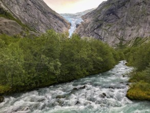 Briksdalsbre, Vestland, Norway, wild water flow through thick forests, with a glacier with