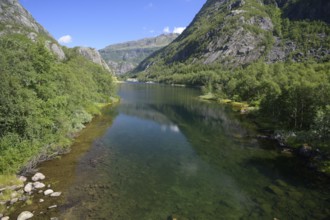 Røldal, Vestland, Norway, Clear water surface of a lake between forested mountains and blue sky in