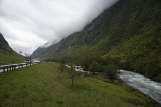 Byrkjelo, Vestland, Norway, truck on road in valley with towering mountains and a river next to it