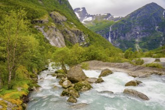 Briksdalsbre, Vestland, Norway, fast-flowing river through green valley with rocks and distant