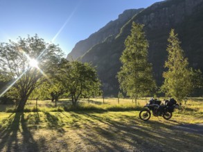 Lysebotn, Rogaland Municipality, Norway, sunrise illuminates a green landscape with a motorcycle in