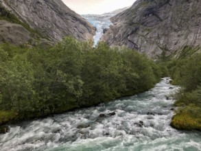Briksdalsbre, Vestland, Norway, A rushing river flows through a green forest, with the