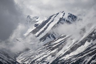 Fog sweeps around mountain peaks with remnants of snow, view from Slaughter Ridge Trail, Cooper