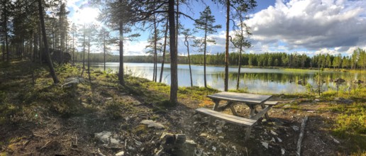 Storsjö Kapell, Jämtlands län, Sweden, panorama of a sunlit forest lake with picnic table in the