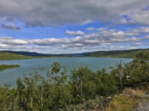 Haugastøl, Viken, Norway, Blue Lake under cloudy sky surrounded by green countryside and mountains,
