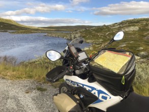 Haugastøl, Viken, Norway, A motorcycle with a map overlooks a quiet seascape in Hardangervidda