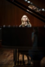 Young woman, pianist, with concentrated facial expression and closed eyes playing on a Steinway &