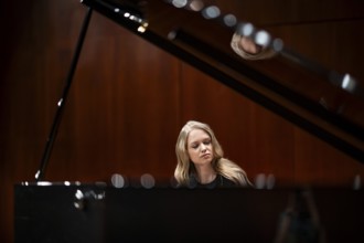 Young woman, pianist, with concentrated facial expression and closed eyes playing on a Steinway &