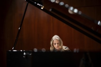 Young woman, pianist, with concentrated facial expression playing on a Steinway & Sons grand piano,