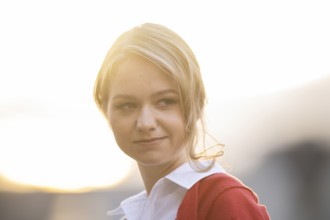 Serious looking young woman in white blouse and red cardigan, in backlight, Stuttgart,