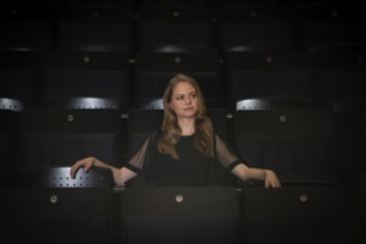 Young woman, pianist, in evening dress, sitting on chair in audience area, Stuttgart,