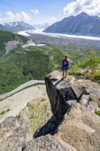 Young woman on a rocky outcrop enjoying the view, view of impressive mountain landscape with