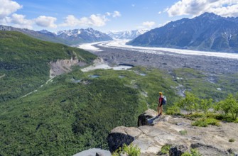 Young woman on a rocky outcrop enjoying the view, view of impressive mountain landscape with