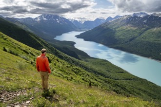Mountaineer enjoys views of blue lake and mountains on Twin Peaks Trail, Eklutna Lake, Chugach