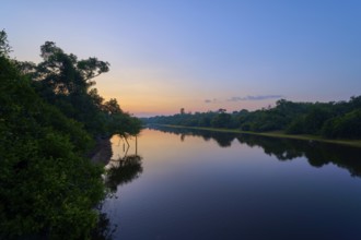 A quiet river morning with shades of blue and orange at sunrise, trees on the shore, Fazenda