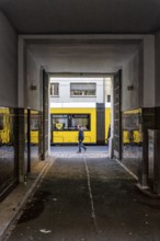 View through a corridor to the backyard onto Chässeestraße with passengers and moving tram, Berlin,