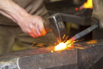 Sparks spray, a blacksmith forging, working at the Ehnert forge in Dresden-Bühlau, Saxony, Germany