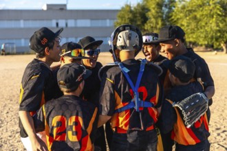 Young baseball players huddling closely together, celebrating and showing strong team spirit before