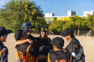 Young baseball players enjoying a moment of camaraderie and success, smiling and embracing after a