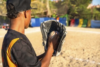 Young baseball player on a sunny field, focused with glove and ball, practicing pitching and