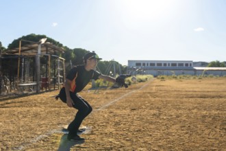 Baseball player in action on a dusty youth sports field, wearing uniform, cap and glove, extending