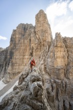 Mountaineer climbs on an exposed rock in the secured Via Ferrata Bocciere Centrale via ferrata,