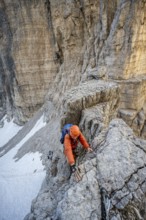 Mountaineer climbs on an exposed rock in the secured via ferrata Bocciere Centrale, Brenta