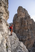 Mountaineer climbs an exposed rock band in the secured Via Ferrata Bocciere Centrale via ferrata,