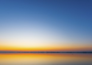 A calm sunrise with a soft color gradient is reflected in the still water of Lake Ddümmer, Dümmer