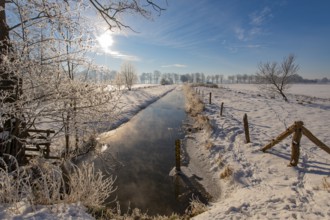 Snowy winter landscape with small river and bright sunshine, Dümmer nature park Park, Lower Saxony,