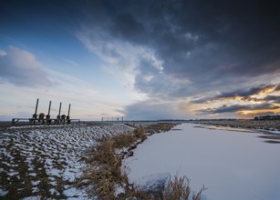 Snowy landscape under dramatic evening sky with clouds on the Hunte near its mouth in Dümmer Lake,