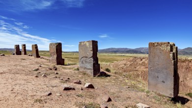Row of standing stone monoliths along an open area with mountains in the background, the