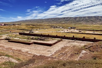 Extensive valley with ruins in the foreground and a mountain range on the horizon, the