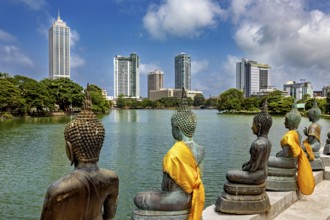Bronze Buddha statues with yellow cloths look at the skyline of a city, the Seema Malaka temple