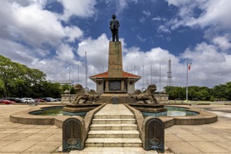 A monument with a statue on a pedestal surrounded by lions and a fountain on a cloudy day, Colombo