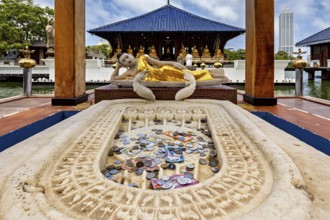 Reclining Buddha statue in a temple with coins in the foreground, The Seema Malaka Temple with the